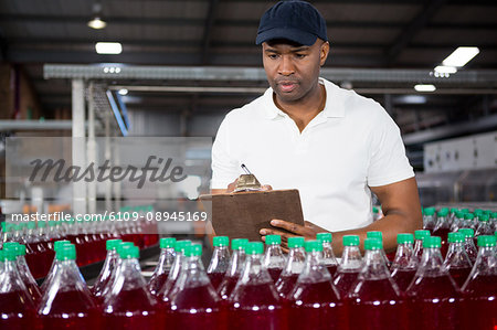 Confident male worker writing on clipboard in factory