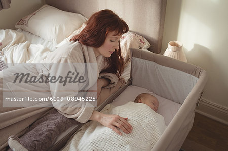 High angle view of mother watching sleeping baby in crib