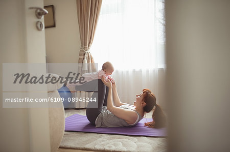 Happy mother and baby exercising on mat at home