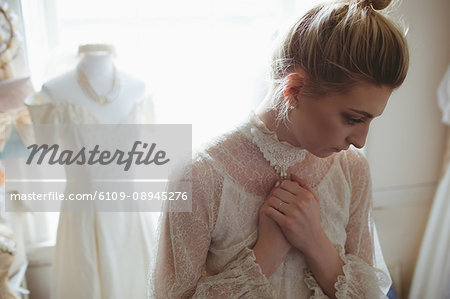 Thoughtful young bride standing in boutique