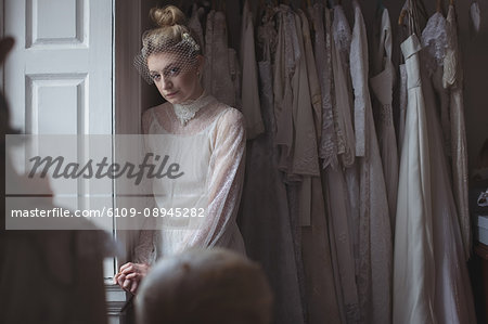 Portrait of young bride standing near window in a boutique Portrait of young bride standing near window in a boutique