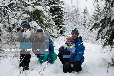 Portrait of happy parents and children playing on snow