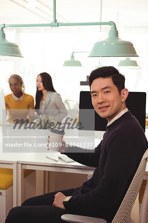 Male executive having coffee at desk in office