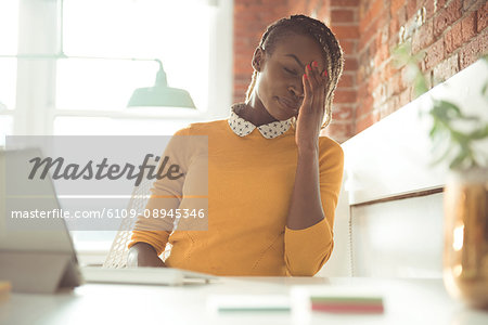 Frustrated female executive sitting at desk in office