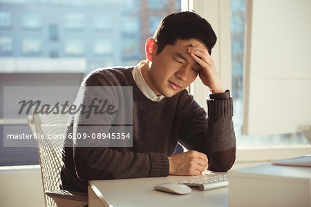 Depressed male executive sitting at desk in office