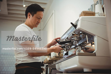 Side view of male barista using espresso machine in cafe