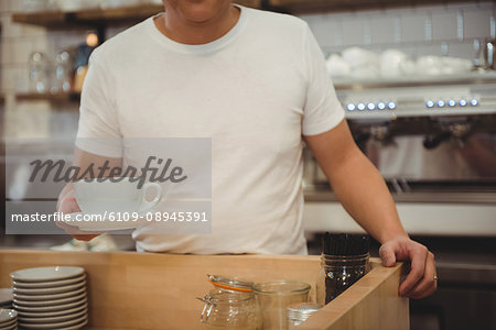 Midsection of male barista holding coffee at cafe