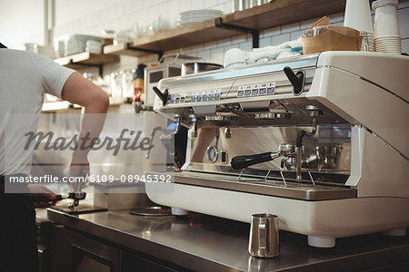 Espresso machine on counter by barista working in coffee shop