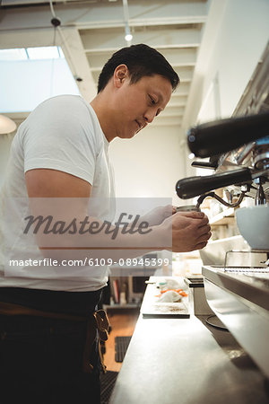 Side view of male barista using espresso machine in coffee shop