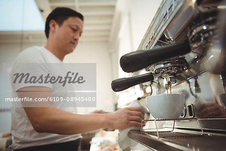 Side view of male barista making espresso in coffee shop