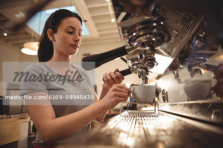 Young female barista making espresso in coffee shop