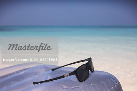 Sunglasses on inflatable raft in tropical blue ocean