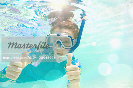 Portrait confident girl snorkeling underwater, gesturing thumbs-up