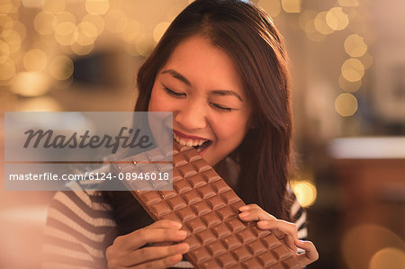 Woman with sweet tooth craving biting into large chocolate bar