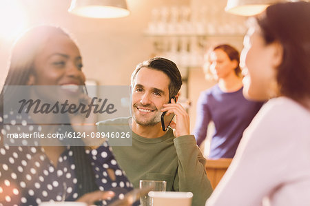 Man talking on cell phone behind women friends talking in bar