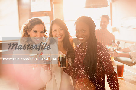 Portrait smiling women friends drinking beer in bar