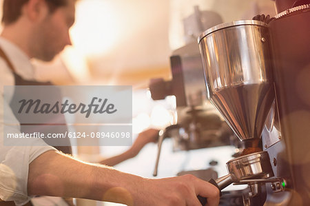 Barista using espresso machine grinder in cafe