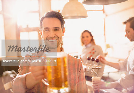 Portrait smiling man toasting beer stein in bar