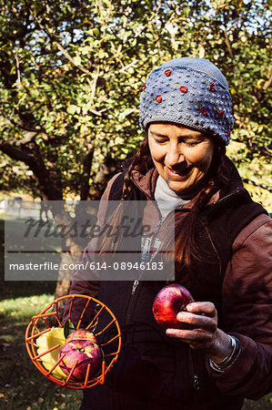 Woman holding fruit picker and fresh apple