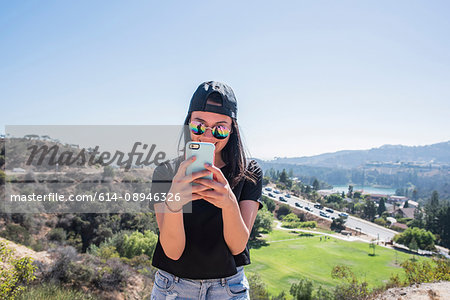 Young woman photographing Hollywood sign, Los Angeles, California, USA