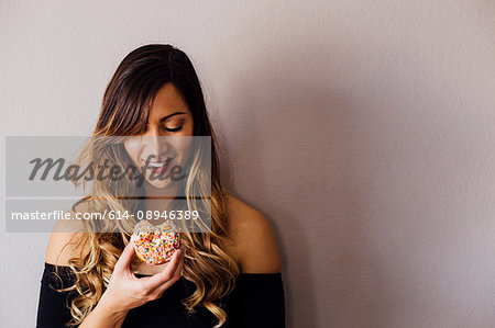 Young woman with long blond hair holding doughnut hole