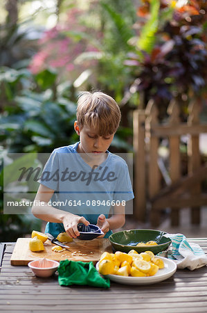 Boy preparing lemons for lemonade at garden table