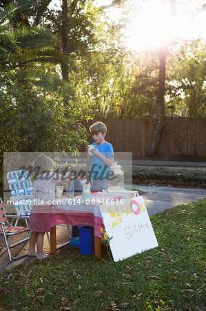 Boy and sister drinking lemonade from lemonade stand in garden