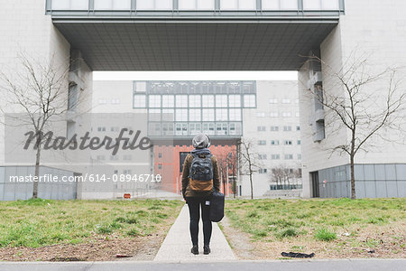 Rear view of female backpacker looking up at office buildings