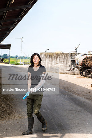 Female organic farmer putting on protective glove at dairy farm