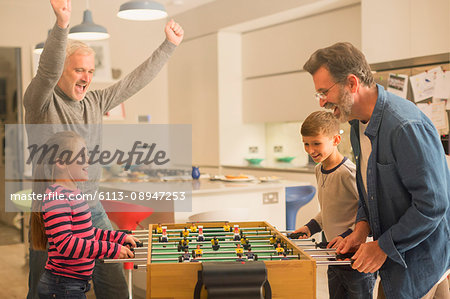 Male gay parents and children playing foosball