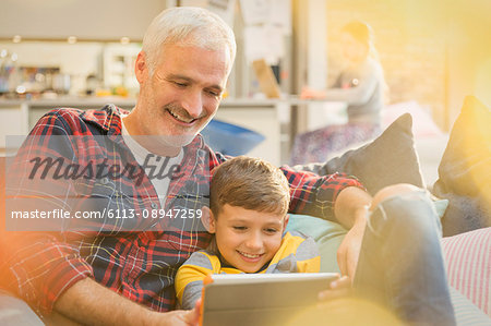 Father and son bonding, sharing digital tablet on sofa