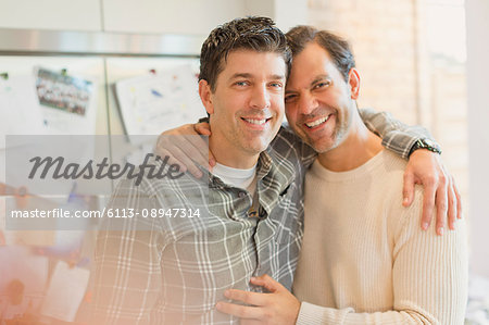 Portrait smiling, affectionate male gay couple hugging in kitchen