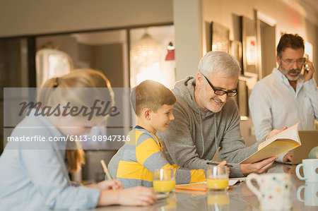 Male gay parents helping children with homework at counter
