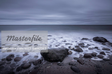 Tranquil overcast gray seascape and rocks on beach, Kalundborg, Denmark