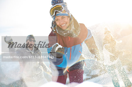 Playful friends enjoying snowball fight in sunny field Playful friends enjoying snowball fight in sunny field