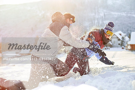 Playful couple enjoying snowball fight in snowy field