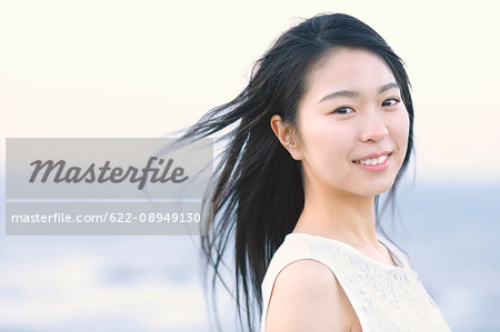 Young Japanese woman in a white dress at a cliff over the sea at sunrise, Chiba, Japan