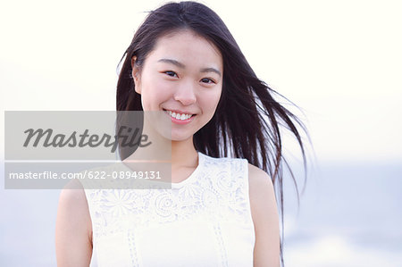 Young Japanese woman in a white dress at a cliff over the sea at sunrise, Chiba, Japan