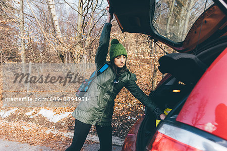 Female hiker unpacking car boot by forest roadside, Monte San Primo, Italy