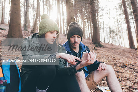 Hiking couple in forest looking at smartphone, Monte San Primo, Italy