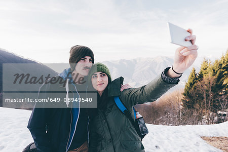 Hiking couple taking selfie in snowy mountains, Monte San Primo, Italy