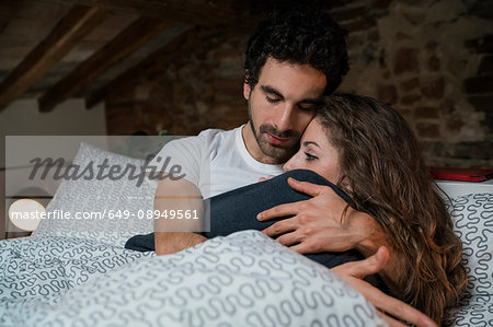 Romantic couple lying in bed hugging