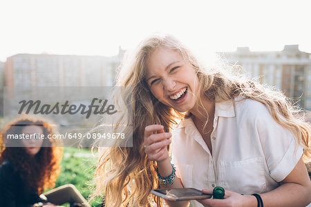 Young woman holding smartphone, laughing