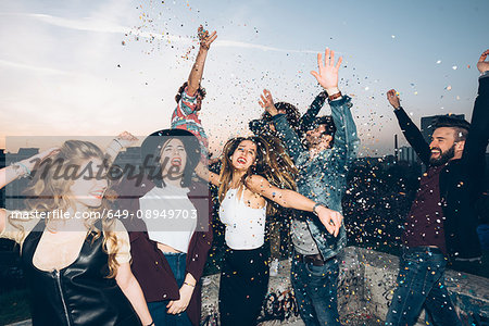 Group of friends dancing, enjoying roof party, confetti in air