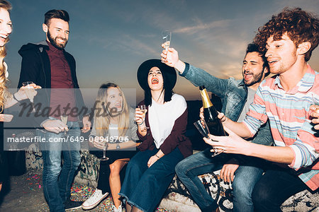 Group of friends enjoying roof party, holding champagne glasses, making a toast