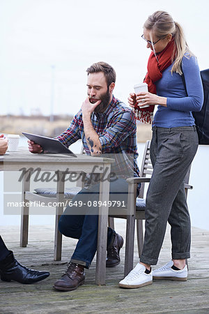 Male and female design team looking at digital tablet on waterfront outside design studio