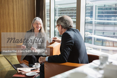 Businessman and businesswoman in coffee area in office, London, UK