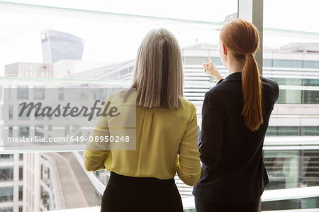Businesswomen standing by window in office, London, UK