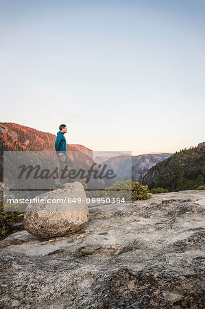 Man looking out from top of boulder, Yosemite National Park, California, USA