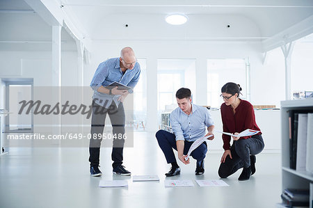 Colleagues working in open plan office looking at blueprints